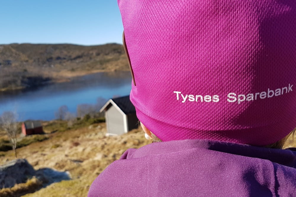 Bakside av lue med tekst Tysnes Sparebank med utsikt over fjell og fjellvann